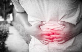 A young man holding his stomach as he was feeling sick.