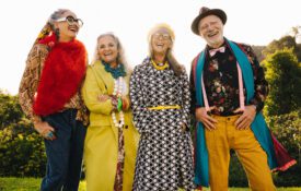 Happy elderly people laughing while standing together in a park.