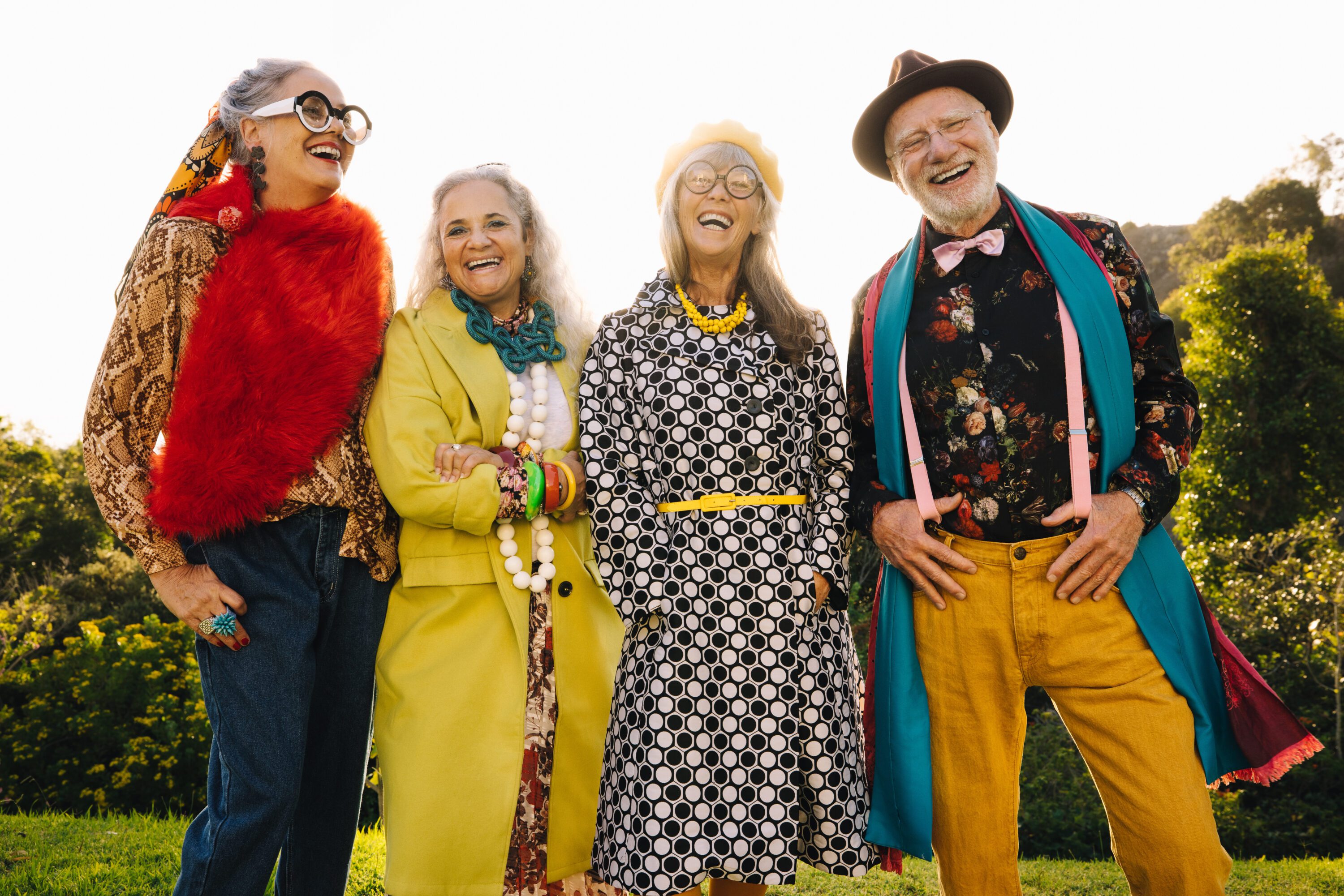 Happy elderly people laughing while standing together in a park.
