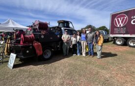 A group of students and volunteers stand beside a piece of heavy equipment from the Alabama Forestry Commission.