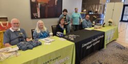 Alabama Extension Master Gardener volunteers sitting at tables and ready to greet conference attendees.
