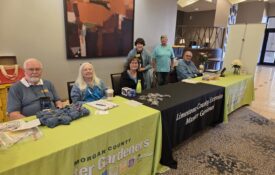 Alabama Extension Master Gardener volunteers sitting at tables and ready to greet conference attendees.
