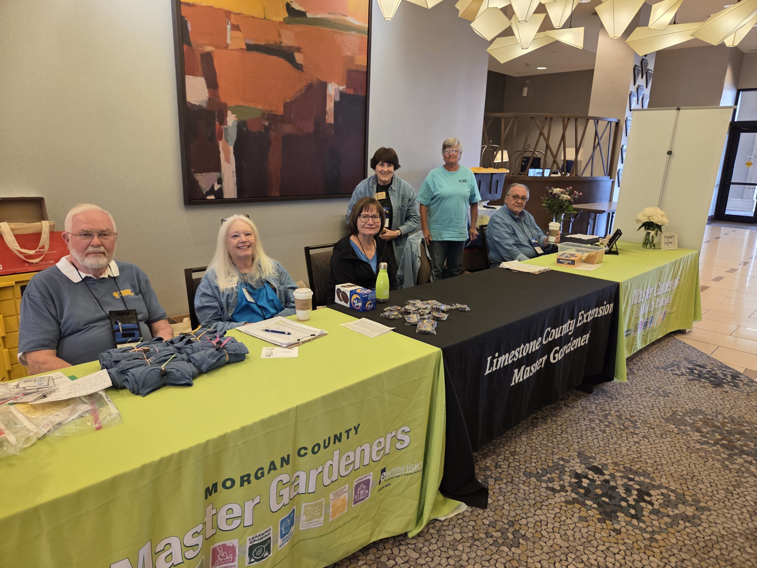Alabama Extension Master Gardener volunteers sitting at tables and ready to greet conference attendees.