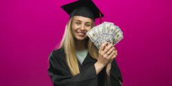 A young lady in a graduation cap and down holding cash.