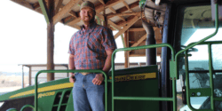 Drew Wendland posing for a picture on a green tractor