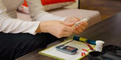 A woman's hand holding diabetes supplies, such as a glucose meter.
