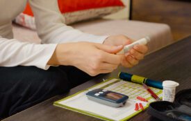 A woman's hand holding diabetes supplies, such as a glucose meter.