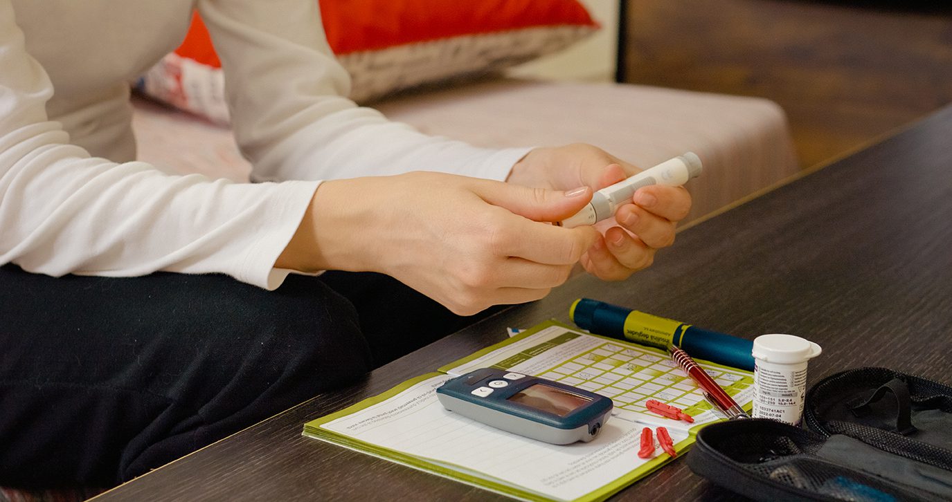 A woman's hand holding diabetes supplies, such as a glucose meter.