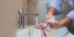 Man using soap and washing hands under the water tap. Hygiene concept hand closeup detail.