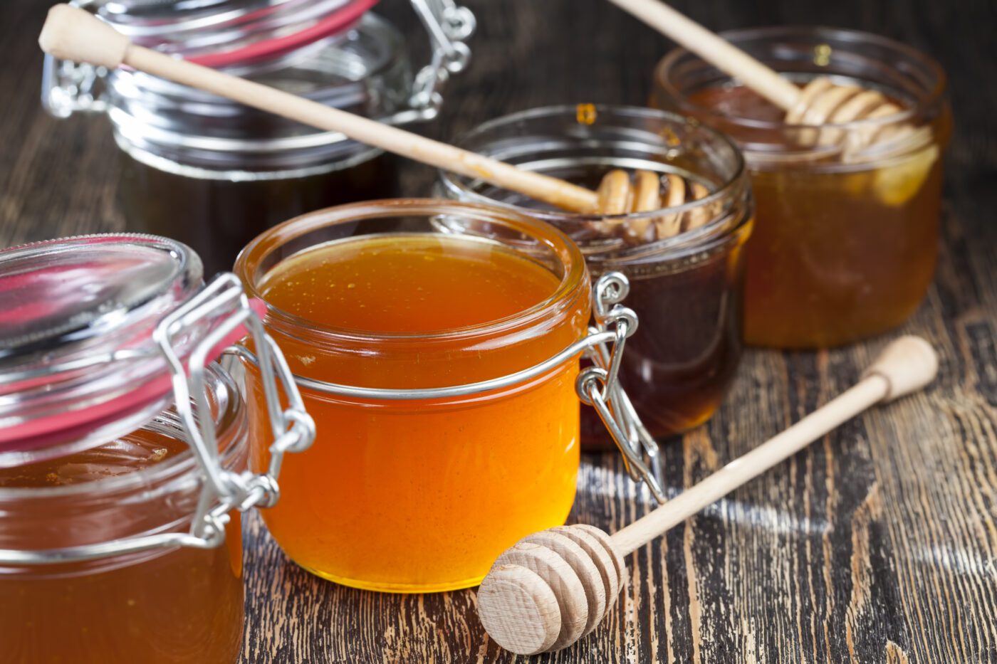 Several jars of honey sitting on a wooden table.