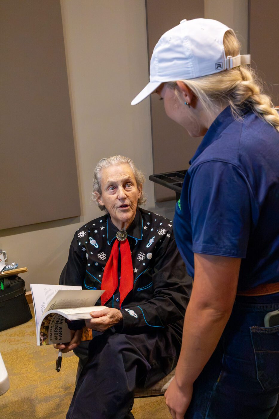 Temple Grandin signing a book and talking with Extension Agent Jenna Schmidt.